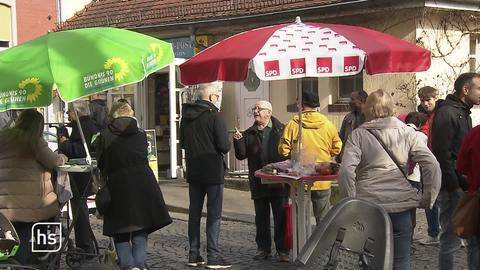 Menschen vor Wahlständen mehrerer Parteien