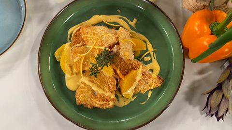 Knuspriger Weißkohlblätter mit Orangen-Ingwer-Mayonnaise garniert mit frischen Orangenscheiben auf einem dunkelgrünen Teller.