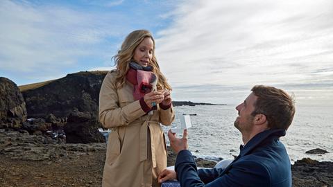 Mann macht Frau am Strand einen Heiratsantrag