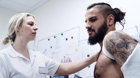 Ein Wrestler wird von einer Rettungssanitäterin behandelt. 