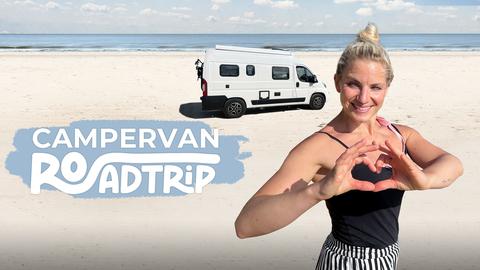 Reporterin Maike Tschorn formt ein Herz am Strand, im Hintergrund ihr Campervan.
