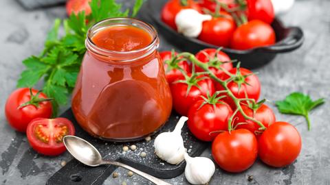 Gläschen mit Tomatensoße, Tomaten, Knoblauch und Kräutern