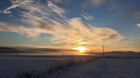 Sonnenuntergang vor einem verschneiten Feld. 