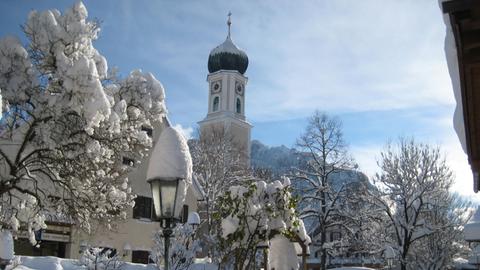 Oberammergau mit Kirchturm mit Schnee bedeckt. 