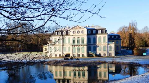 Ein Schloss vor einem See mit vereisten Grünflächen.