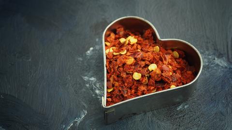 Chiliflocken in einem Keksausstecher in Herzform.
