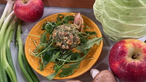 Ein großer gefüllte Champignon mit Handkäse und Apfel, auf einem gelben Teller garniert mit viel Rucola und Apfelscheiben.