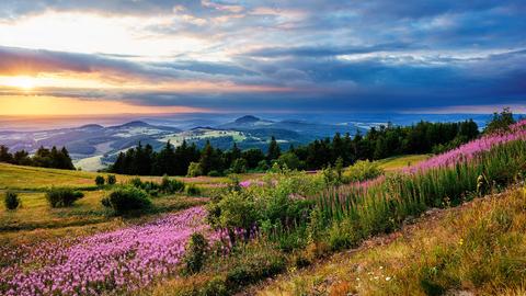 Ausblick von der Wasserkuppe auf hügelige Landschaft bei Sonnenuntergang.