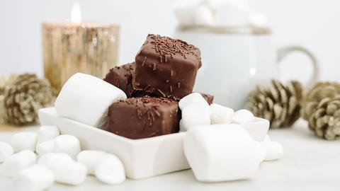 Petit Four mit dunkler Schokolade und Marshmallows in weihnachtlicher Dekoration.