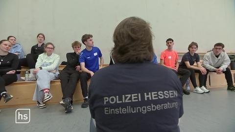 Ein Polizist spricht mit interessierten Schülern.