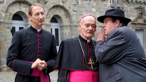 Pfarrer Braun (Ottfried Fischer, re.) verrät Monsignore Mühlich (Gilbert von Sohlern, li.) und Bischof Hemmelrath (Hans-Michael Rehberg) ein Geheimnis.