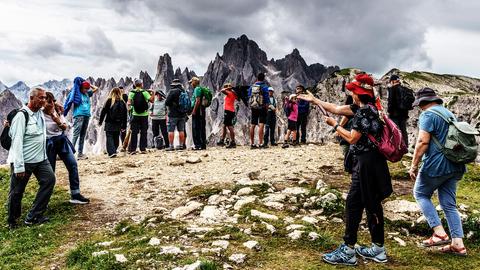 Sehr viele Menschen stehen auf einem Berggipfel.