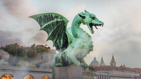 Ein Drache der Drachenbrücke in Ljubljana im Nebel vor wolkigem Hintergrund.