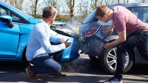 Zwei junge Männer begutachten den Schaden an ihren Autos, der bei einem Auffahrunfall zustande kam.