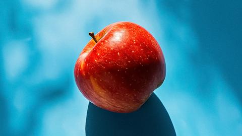 Großer roter Apfel und Schatten auf Blau.